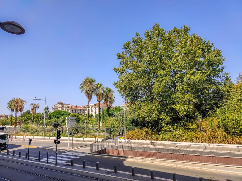 a bus driving down a road with palm trees at Aparthotel AMMI Vieux Nice in Nice
