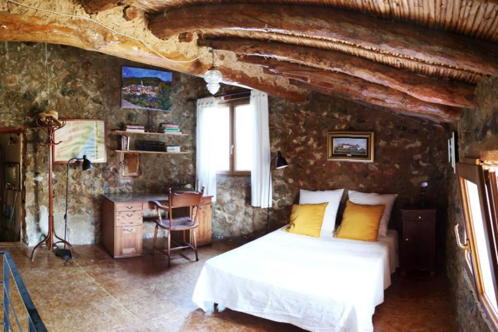 a bedroom with a bed in a stone wall at La Casa de Piedra, una ventana al paraíso in Matet