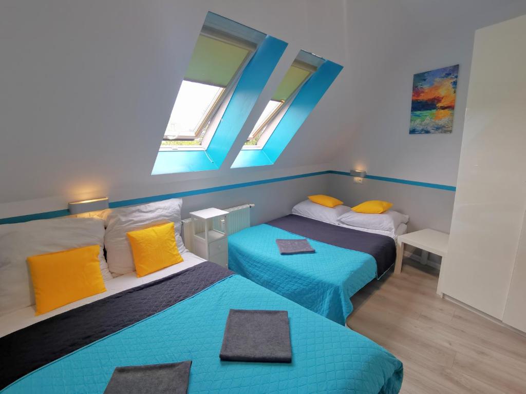 コウォブジェクにあるGood Spirit Roomsの青と黄色の枕が備わる客室のベッド2台