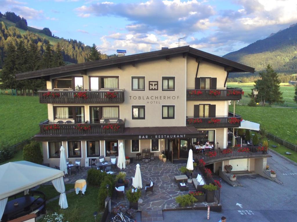 an aerial view of a hotel with tables and umbrellas at Hotel Toblacherhof in Dobbiaco