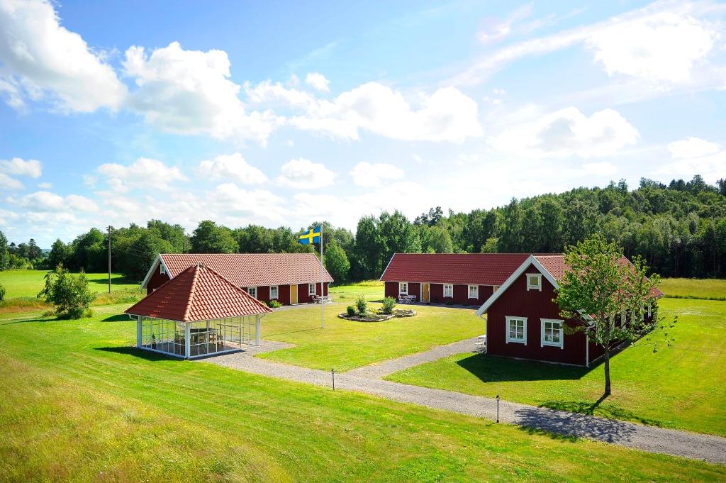 two buildings in a field with trees in the background at Hagbards By Gårdspensionat in Slöinge