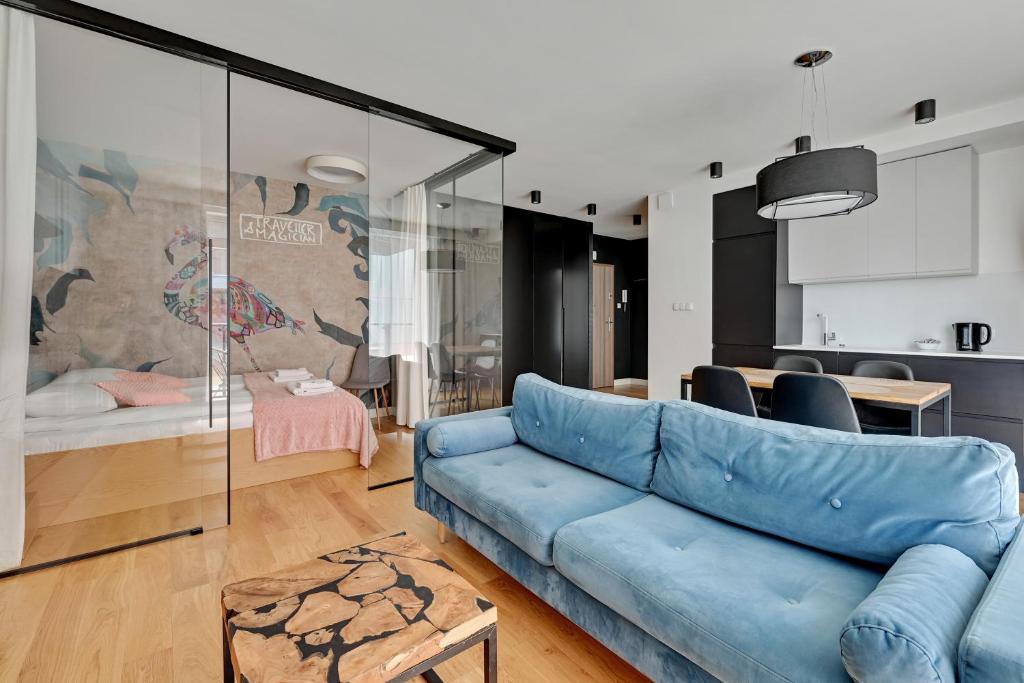 ein Wohnzimmer mit einem blauen Sofa und einer Küche in der Unterkunft Dom & House - Apartments Chmielna Park in Danzig