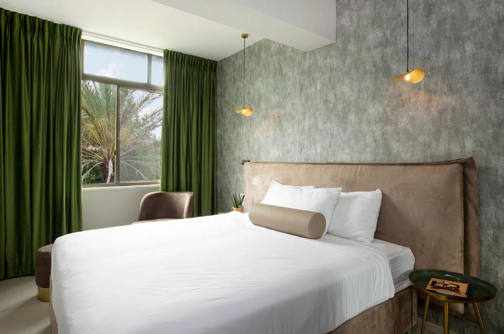 a bedroom with a large bed with green curtains at Eden Inn in Zikhron Ya‘aqov
