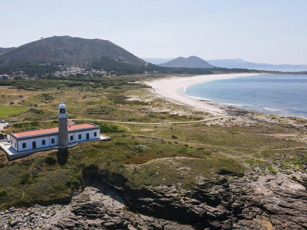 a lighthouse on a hill next to a beach at Hotel Faro Lariño in Lariño