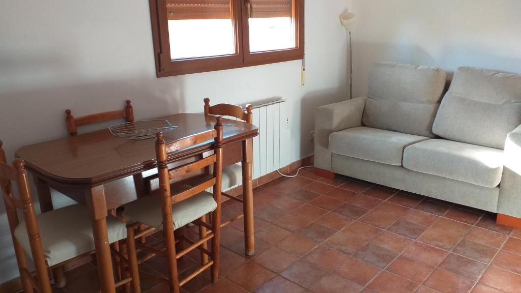 ein Wohnzimmer mit einem Tisch, einem Sofa und einem Stuhl in der Unterkunft Casa la Era in Salas Bajas