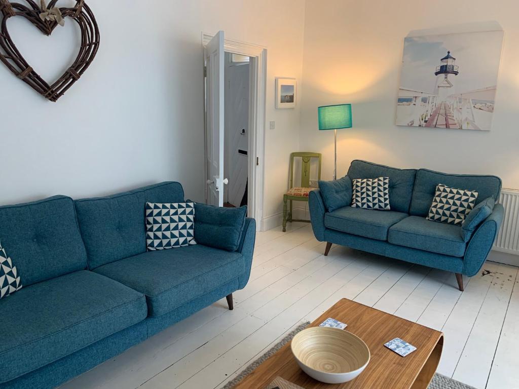 een woonkamer met twee blauwe banken en een tafel bij Hobbes Cottage, pets allowed in Tenby