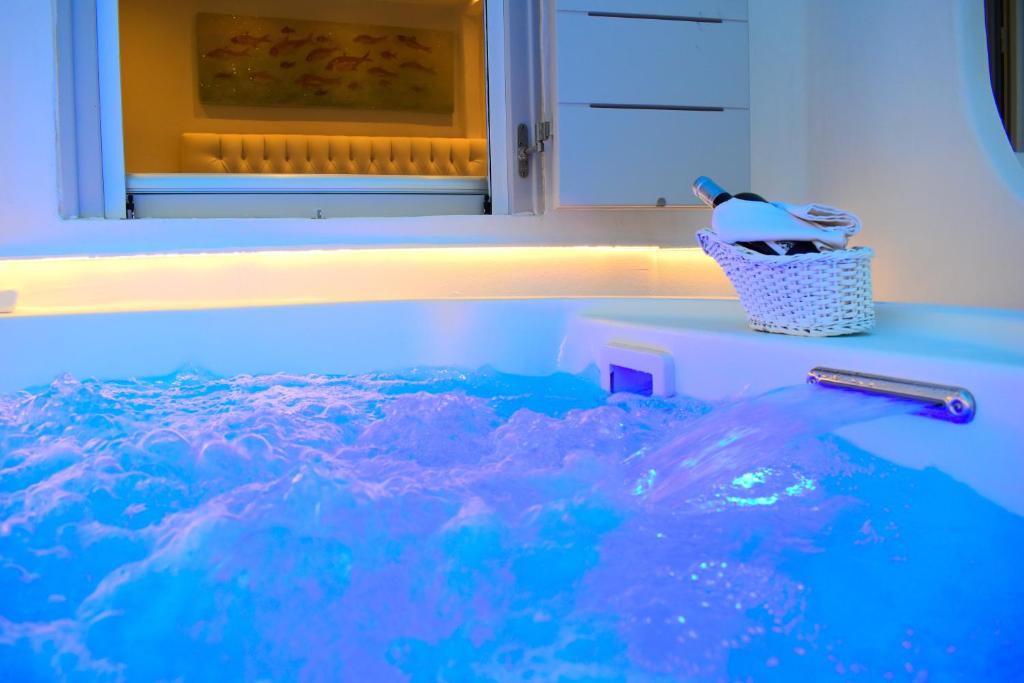a tub filled with blue water with a toothbrush at Ariana Eco Suites Adults Only in Fira
