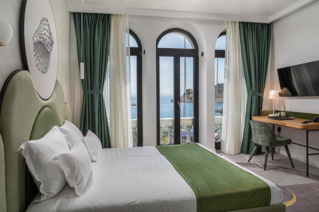 a hotel room with a bed and a desk and windows at Heritage Hotel Porin Makarska in Makarska
