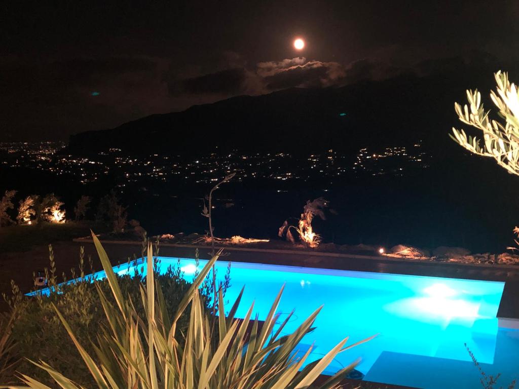 uma piscina à noite com a lua ao fundo em Villa Minù Scopello em Scopello