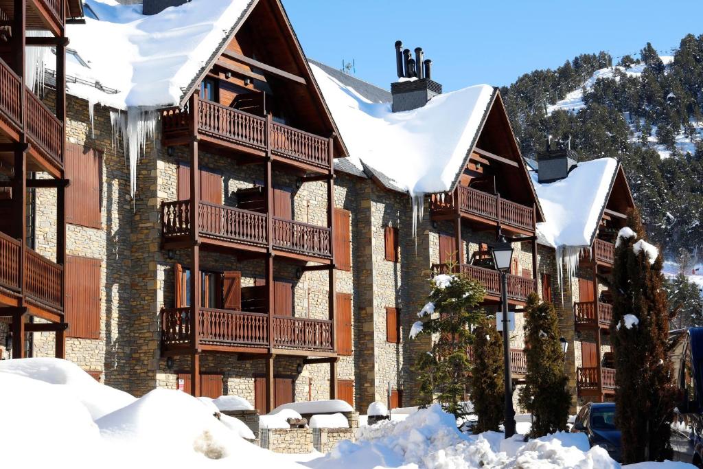 un grand bâtiment avec de la neige au sol dans l'établissement Apartarent La Pleta y Nin Cota 1700, à Baqueira-Beret