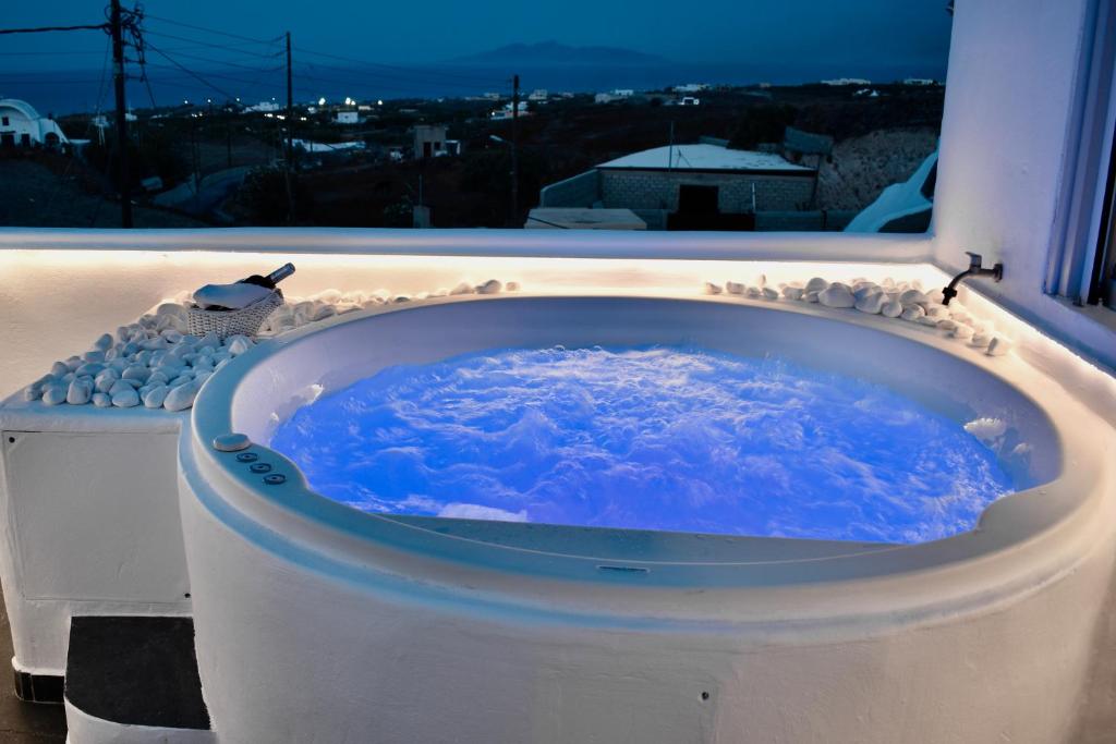 a bath tub with blue water in front of a window at Ariana Eco Suites Adults Only in Fira