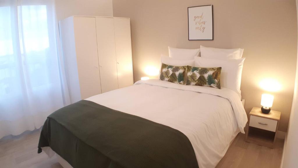 una camera da letto con un grande letto bianco con due lampade di CasaCity Orléans Sud - 2 chambres - parking privé a Orléans