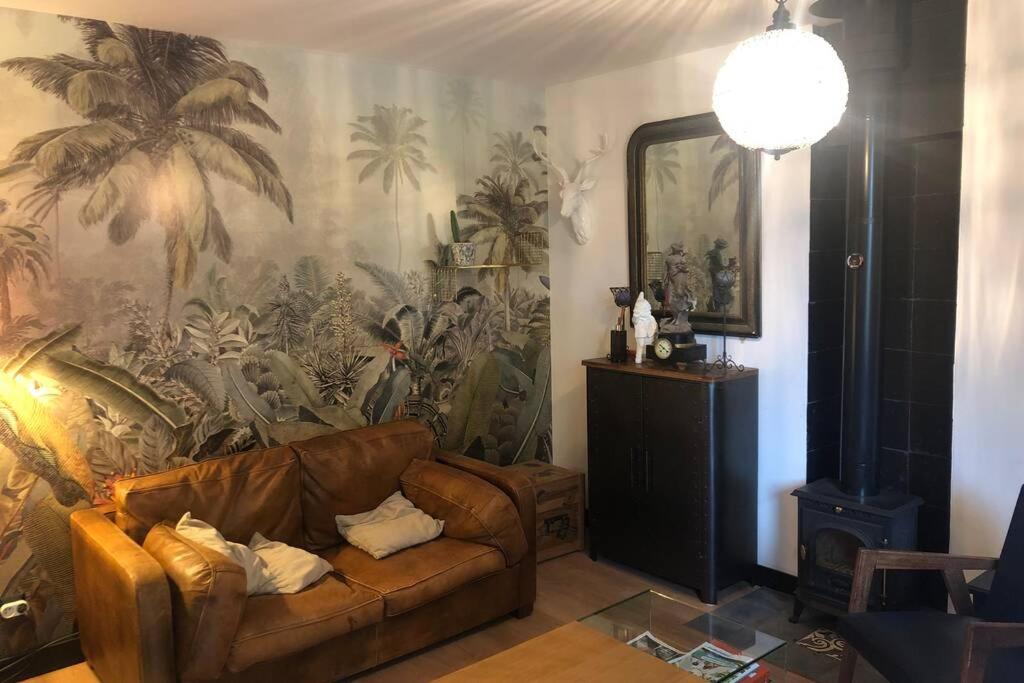 a living room with a couch and a large mural at La petite maison dans la jungle in Chartres-de-Bretagne