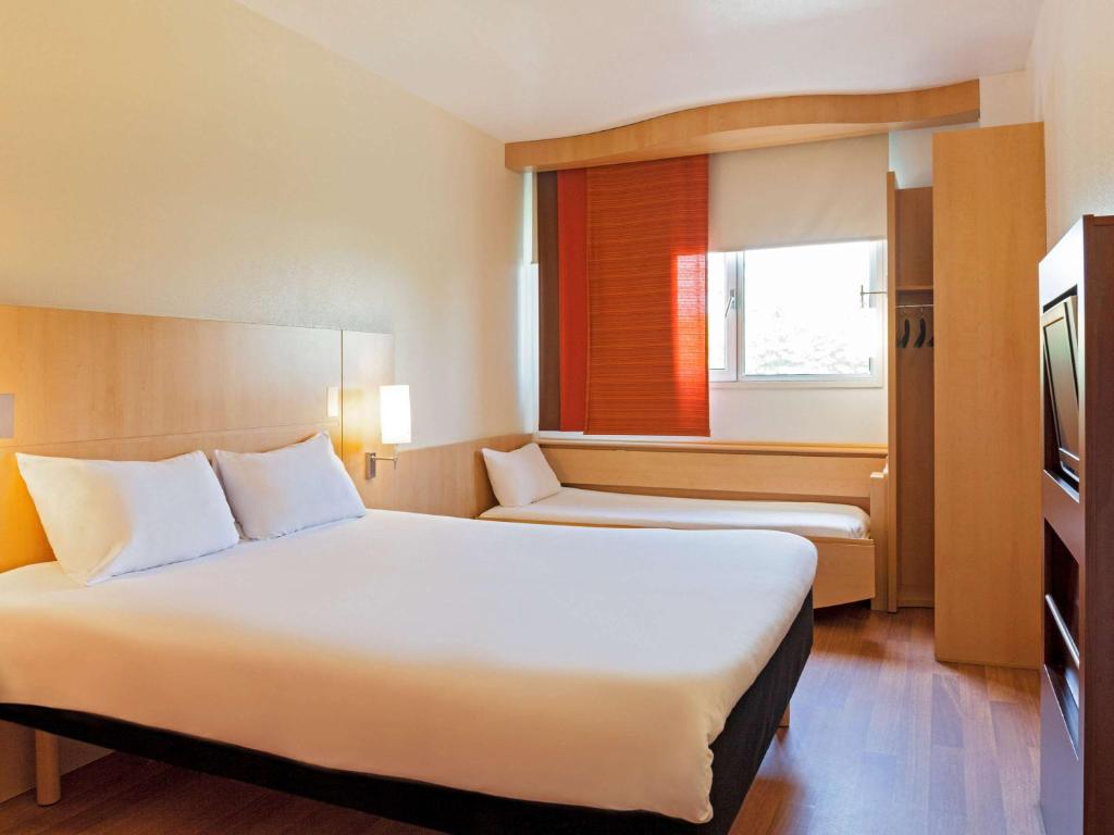 a hotel room with two beds and a window at ibis Paris Porte d'Italie in Gentilly