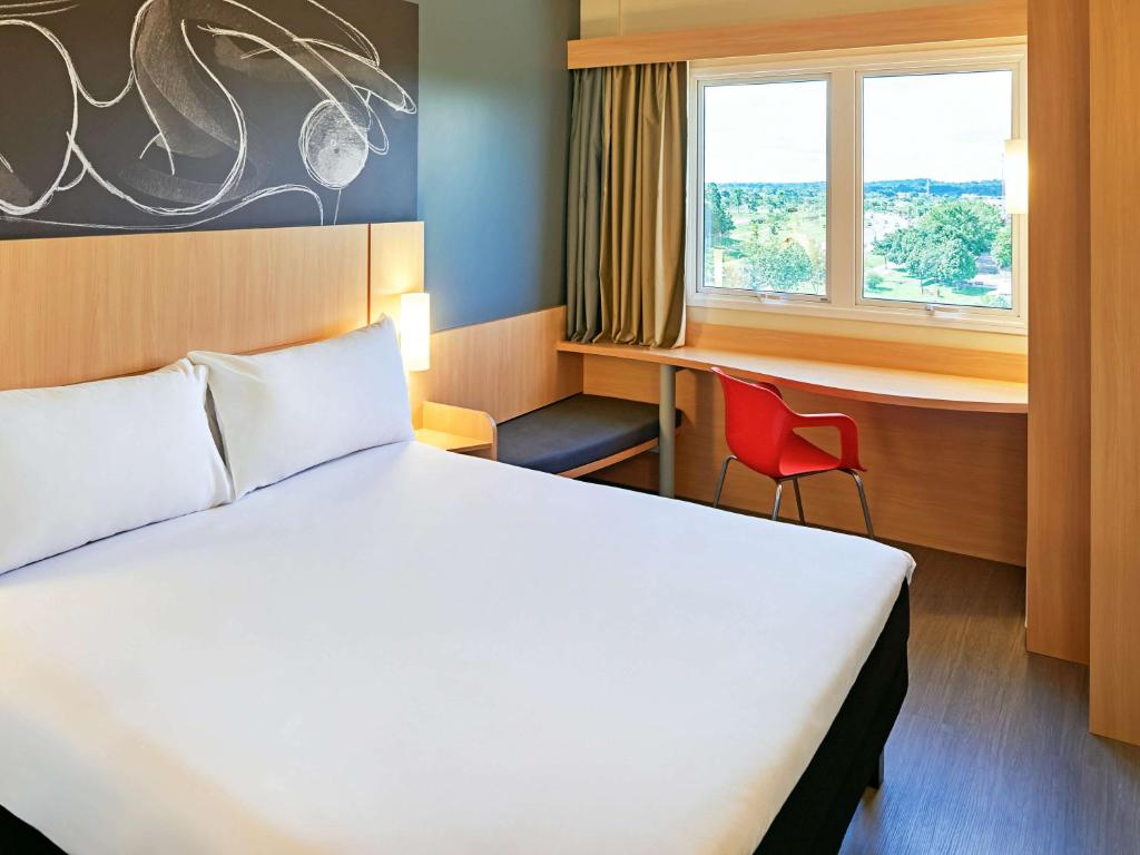 um quarto de hotel com uma cama, uma secretária e uma janela em ibis Rio Branco em Rio Branco