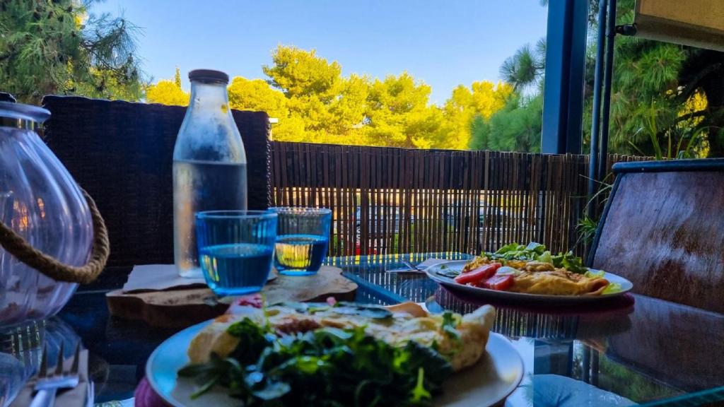 einen Tisch mit zwei Teller Essen und einer Flasche in der Unterkunft South Coast Voula Beach Sea RIVIERA Suite in Athen