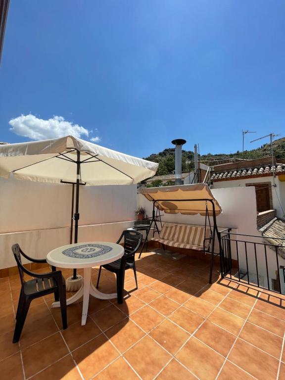 patio ze stołami i parasolami na dachu w obiekcie Casa rural Los Abuelos w mieście Monachil
