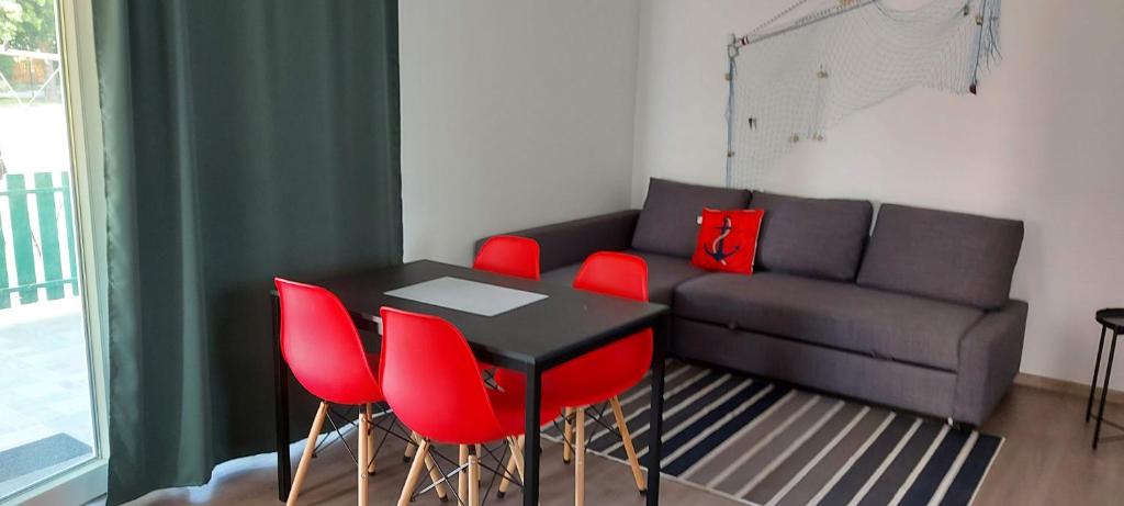 - un salon avec une table noire et des chaises rouges dans l'établissement Gesztenyés Apartmanház Tiszaalpár, à Tiszaalpár