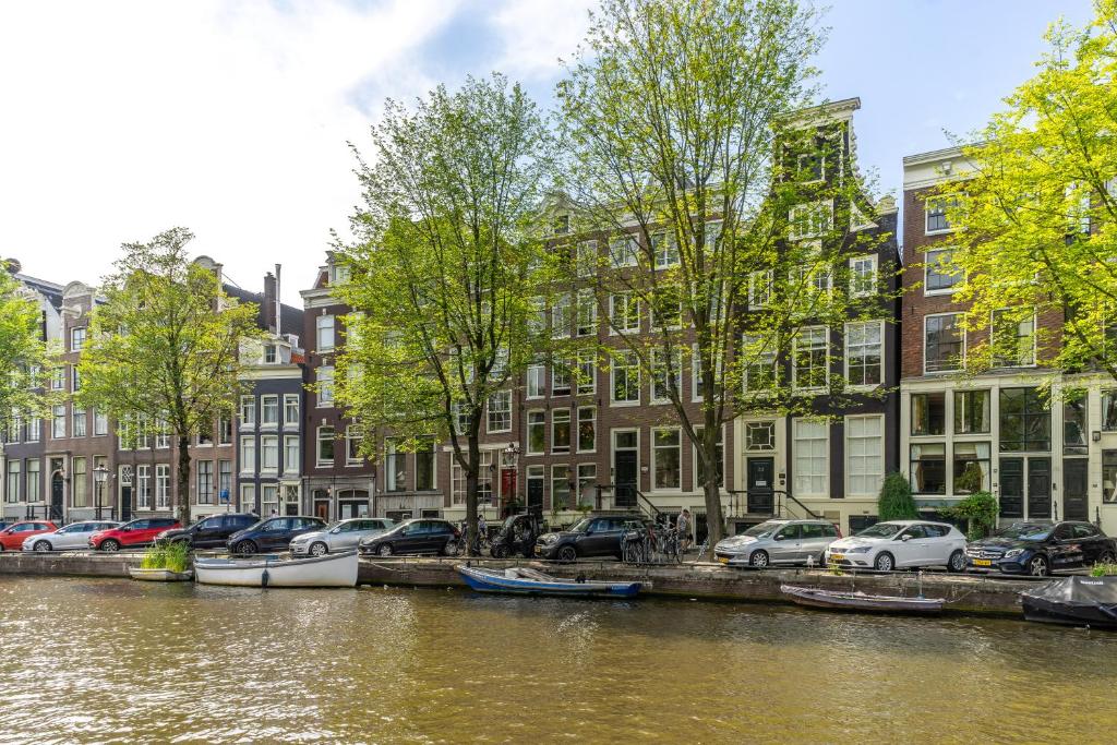un canale con macchine parcheggiate accanto agli edifici di B&B Singel Suites ad Amsterdam