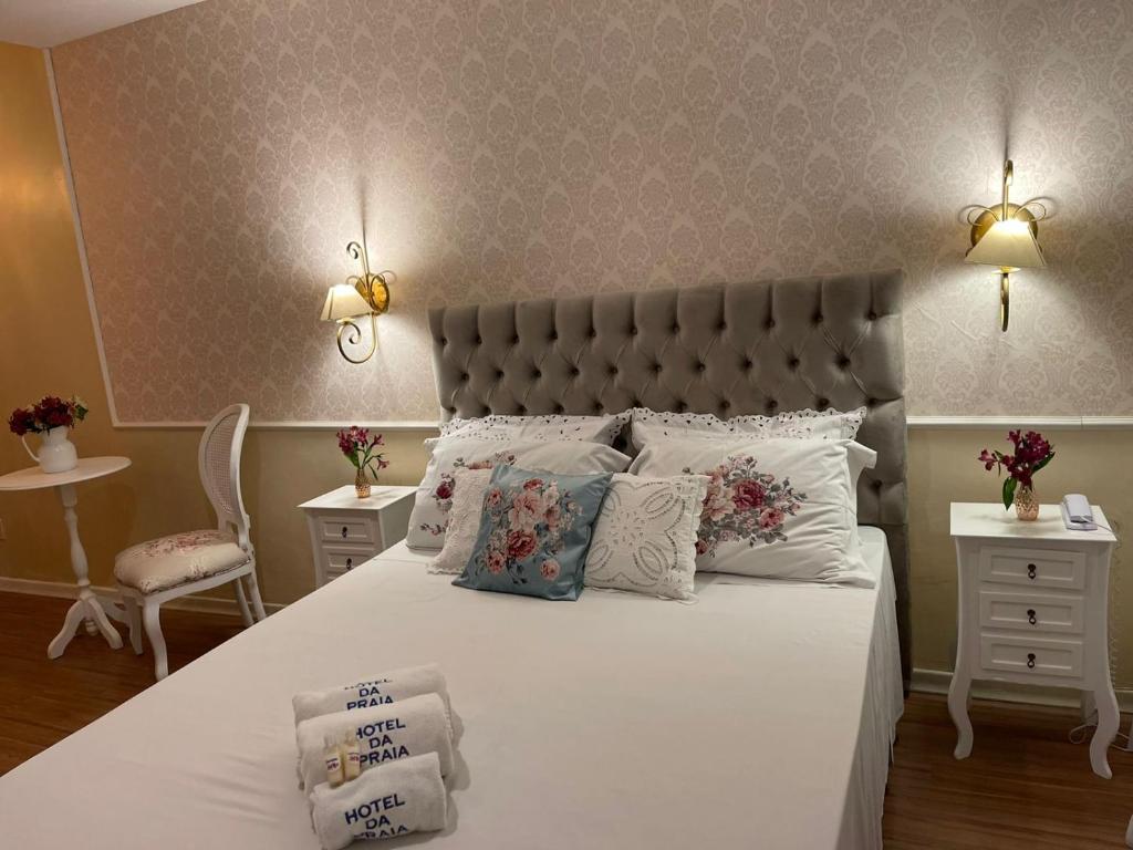 um quarto com uma cama grande com lençóis brancos e almofadas em Hotel da Praia em Vila Velha
