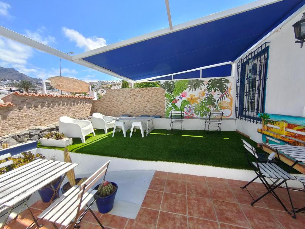 阿德赫的住宿－Endless Summer House，庭院配有白色椅子和蓝色遮阳伞