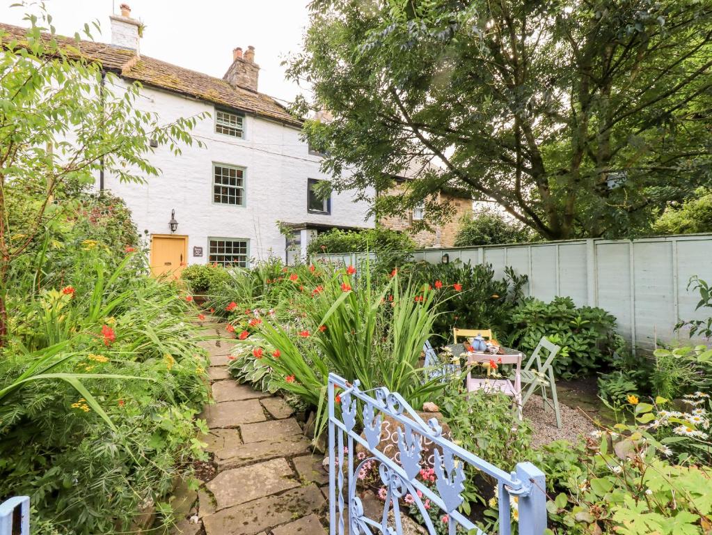 um jardim em frente a uma casa branca com flores em Bonny Bits Cottage em Alston