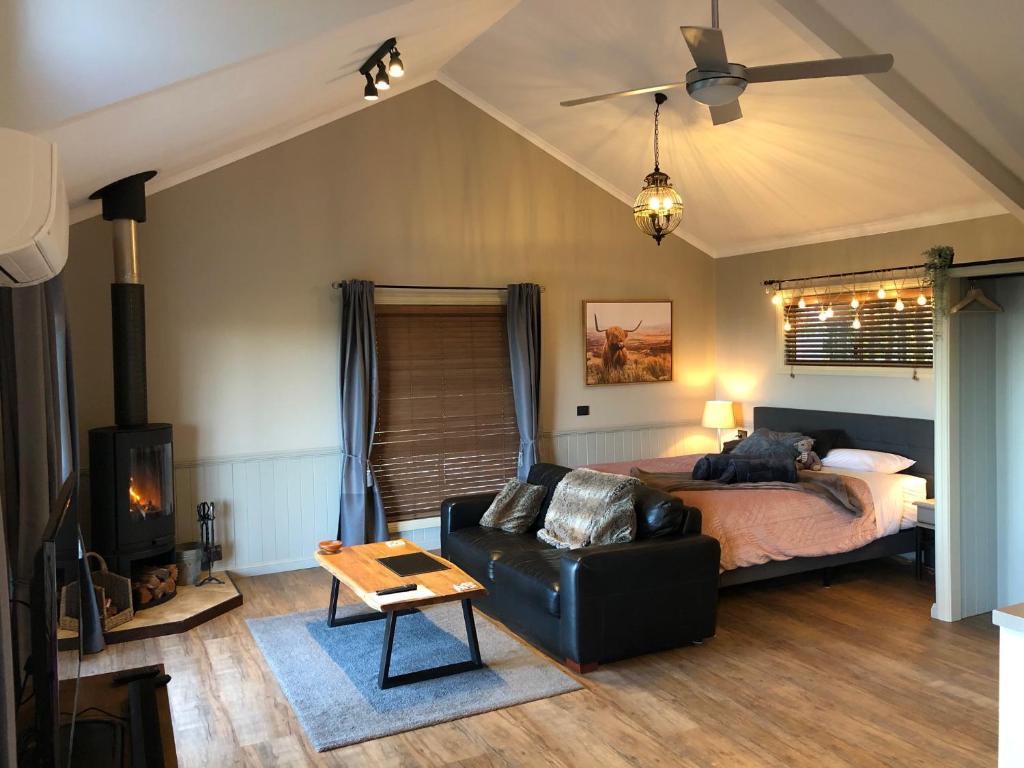 um quarto com uma cama e um sofá de couro preto em Maleny Luxury Cottages em Maleny