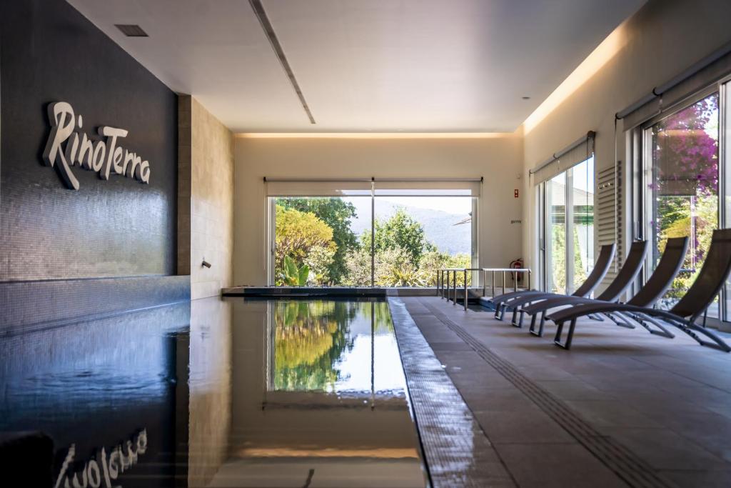 a swimming pool in the middle of a room with chairs at Rinoterra Minho in Caminha