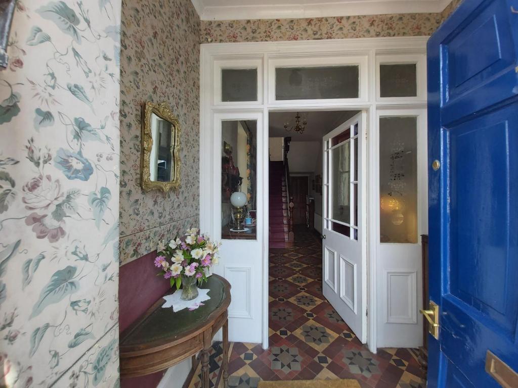 a hallway with a blue door and a vase of flowers at The Fieldings in Truro