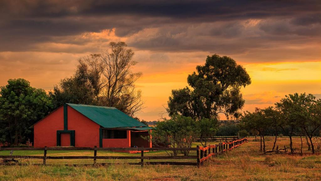 un granero rojo con techo verde en un campo en Thaba Manzi Ranch, en Magaliesburg