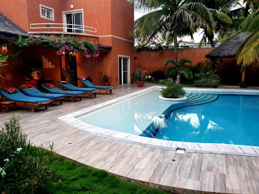 uma piscina em frente a um edifício com cadeiras azuis em Safari Village Saly em Saly Portudal