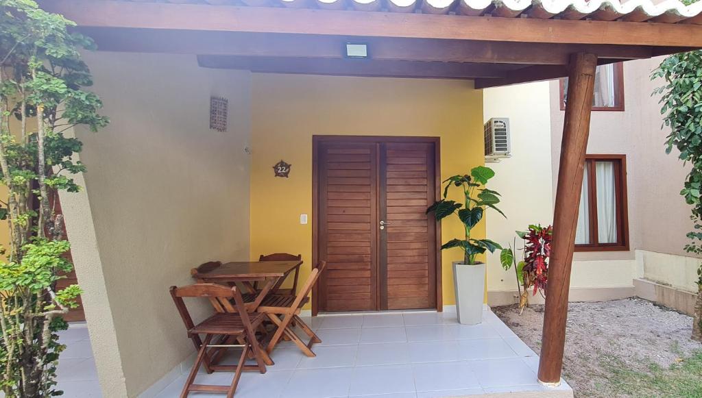 patio ze stołem, krzesłami i drewnianymi drzwiami w obiekcie Flat no bosque da praia Pipa-RN w mieście Pipa