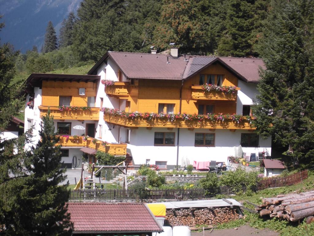 un gran edificio blanco y amarillo con flores. en Haus Waldheim, en Sankt Leonhard im Pitztal