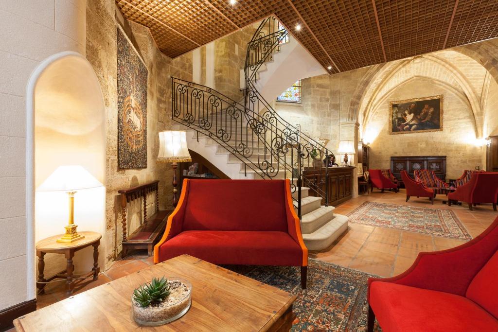 a living room with a staircase and a red chair at Hôtel des Augustins in Aix-en-Provence