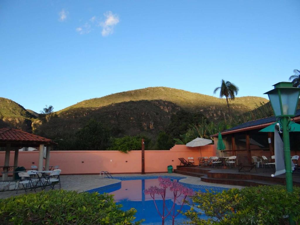 a resort with a swimming pool with a mountain in the background at Pousada Banana Cipó in Serra do Cipo