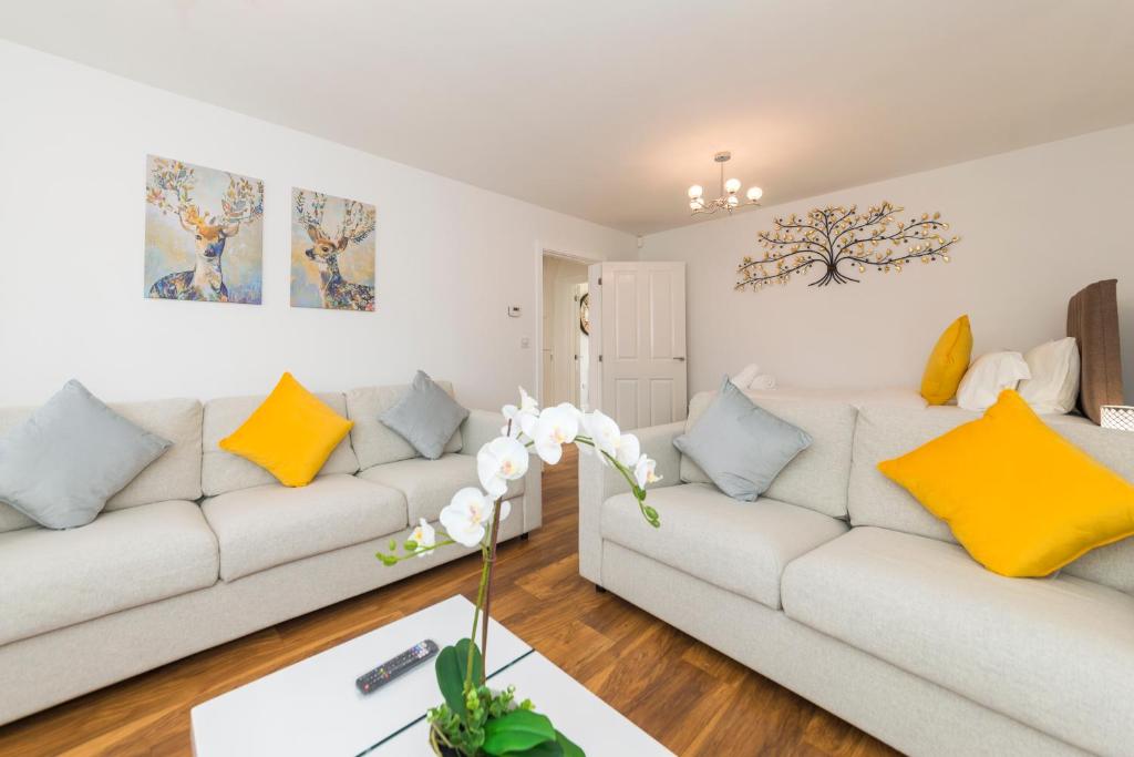 a living room with two white couches and yellow pillows at Greenfield's Oxlade Home - Modern 3 Bed room House, Langley, Slough in Slough