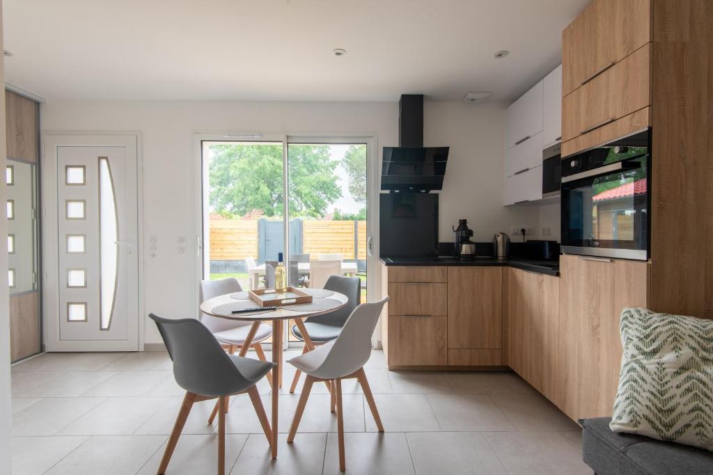 une cuisine et une salle à manger avec une table et des chaises dans l'établissement Ethnia, maison avec spa, jardin privé proche Lac, à Biscarrosse