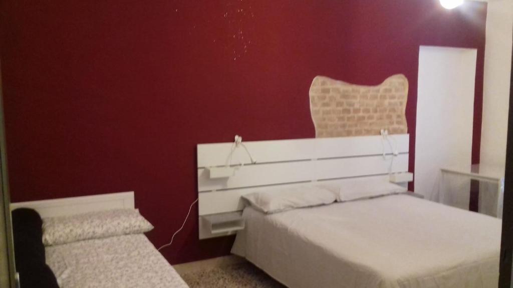 1 dormitorio con 2 camas y pared roja en B&B i colori del Monferrato, en Montiglio