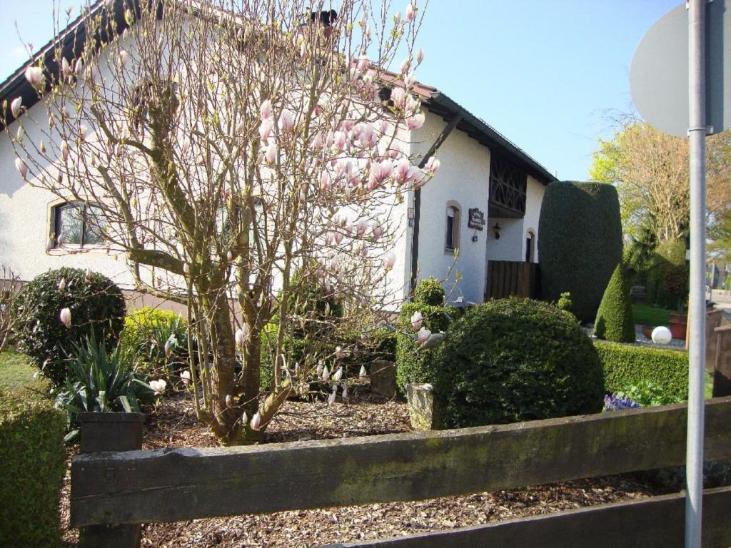 ein Haus mit einem blühenden Baum im Hof in der Unterkunft Landhaus Strangmüller in Bad Füssing