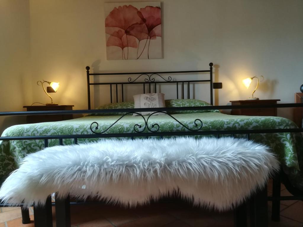 a bed with a black frame with a white furry bench at La Casa Del Borgo in Beverino