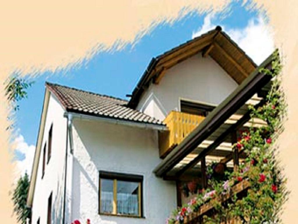 a white house with flowers on the side of it at Ferienwohnung Zucker in Grafenau