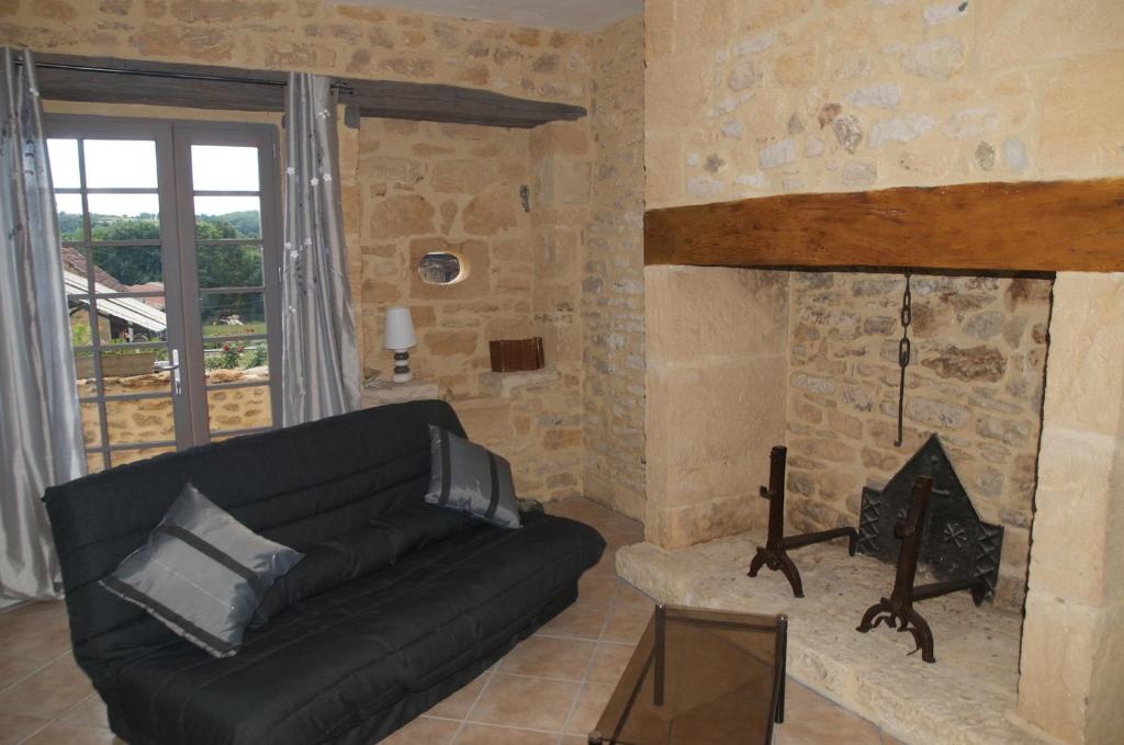 uma sala de estar com um sofá preto e uma lareira em Gite de Charme em Calviac