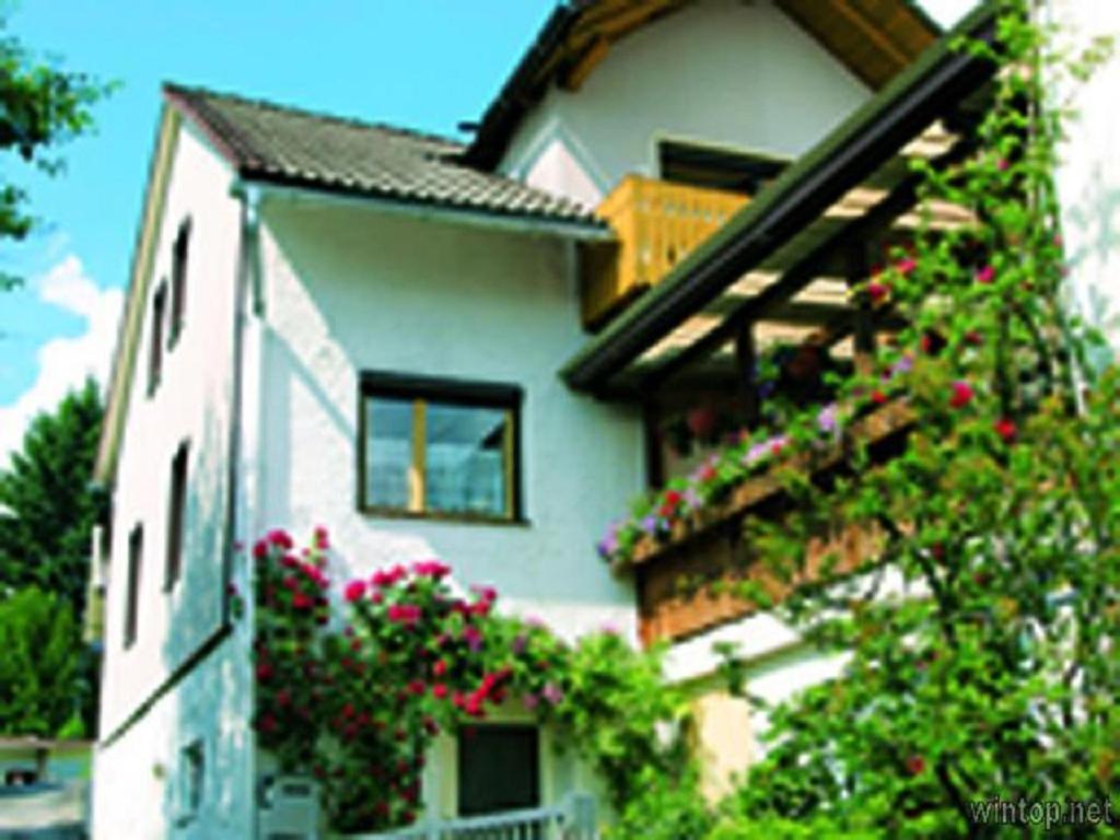 une maison blanche avec des fleurs sur son côté dans l'établissement Ferienwohnung Zucker, à Grafenau