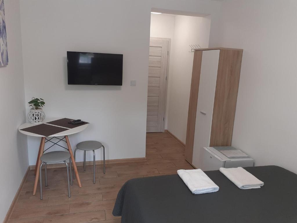 a room with a bed and a table and a television at APARTAMENTY CENTRUM PIŁSUDSKIEGO in Białystok