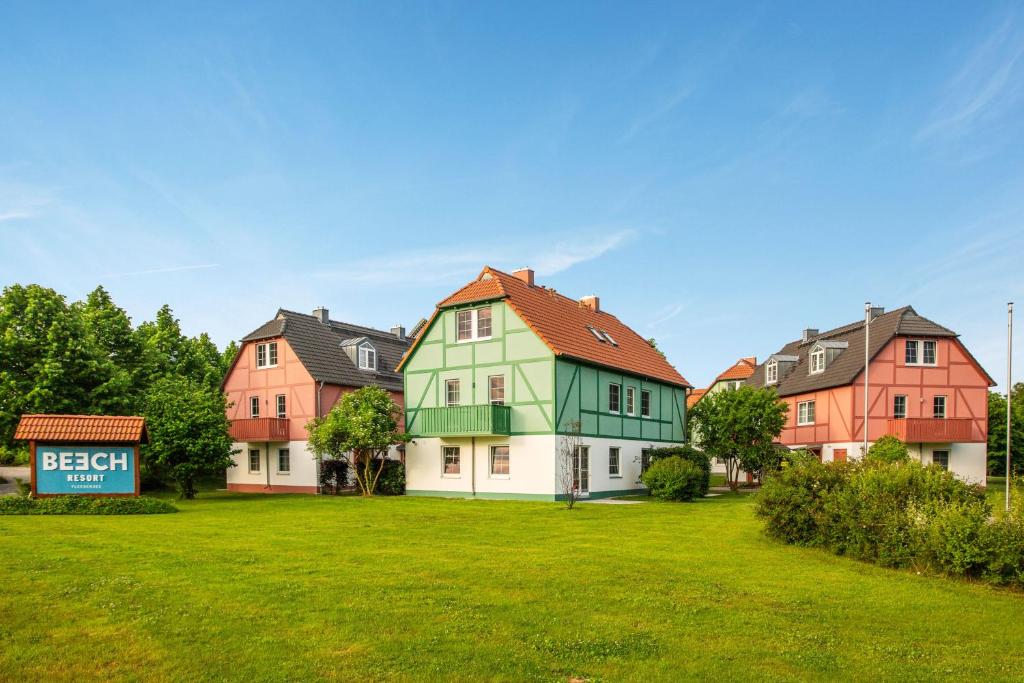 a group of houses with a sign in a field at BEECH Resort Fleesensee in Göhren-Lebbin