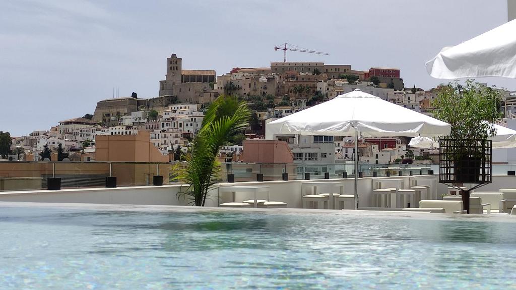 a beach with umbrellas and a pool at El Puerto Ibiza Hotel Spa in Ibiza Town