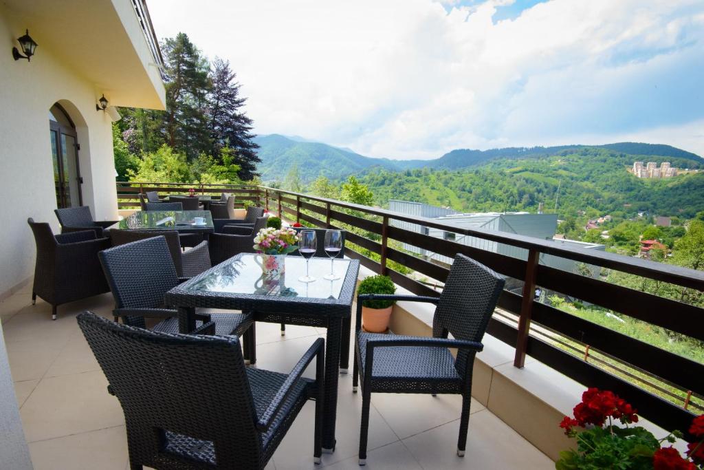 a balcony with a table and chairs and mountains at Pensiunea Toscana in Braşov