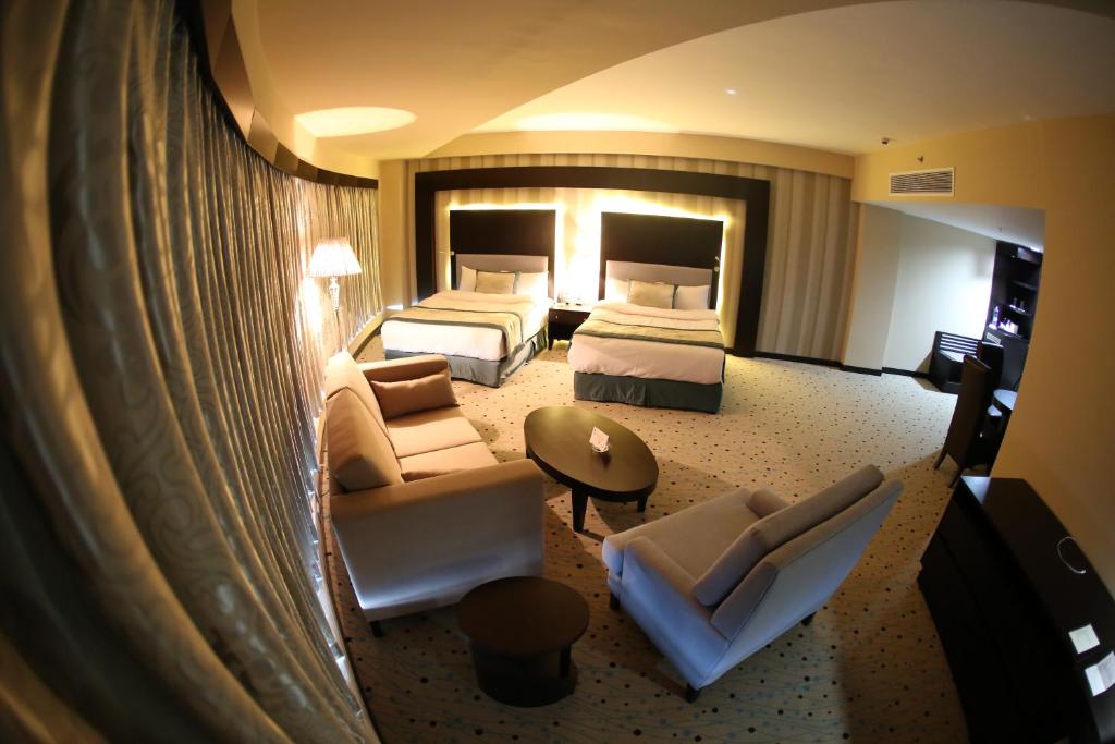 um grande quarto de hotel com duas camas e um sofá em Palestine Plaza Hotel em Ramala