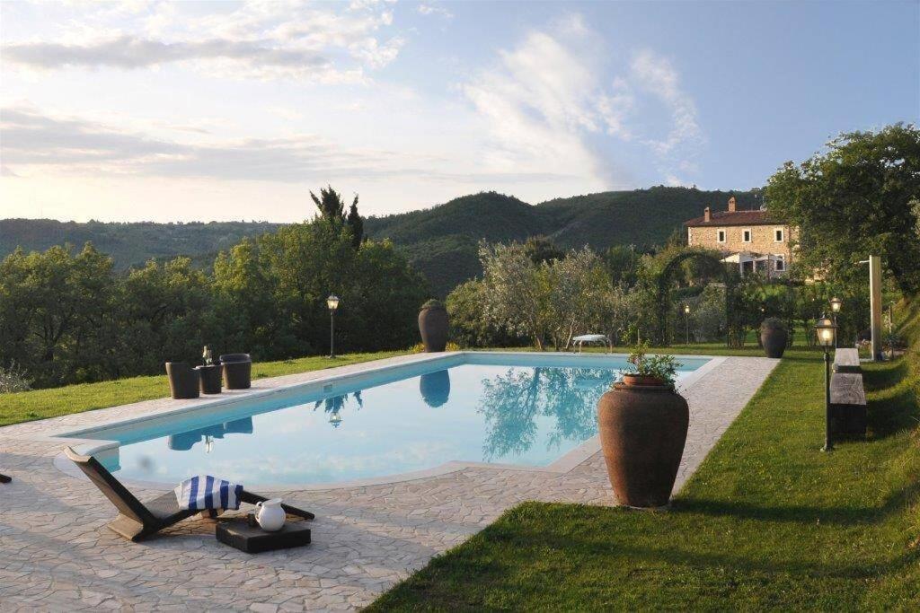 een zwembad met een stoel en een huis bij Exclusive Villa Parrano - countryside with pool in Parrano