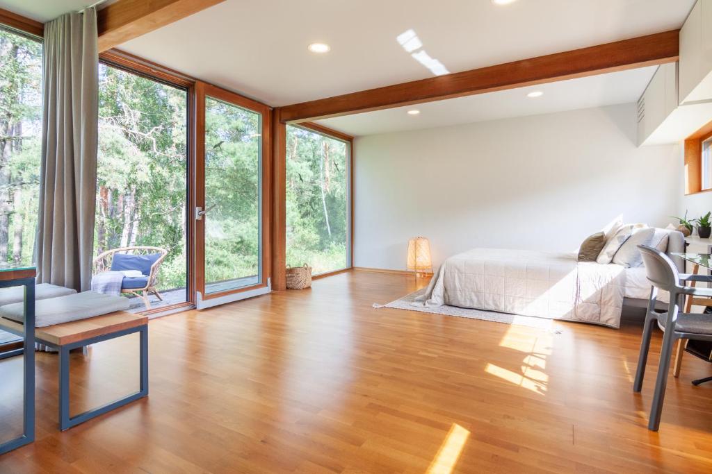 a bedroom with a bed and large windows at KEDRO NAMELIS, Cedar house in Varėna